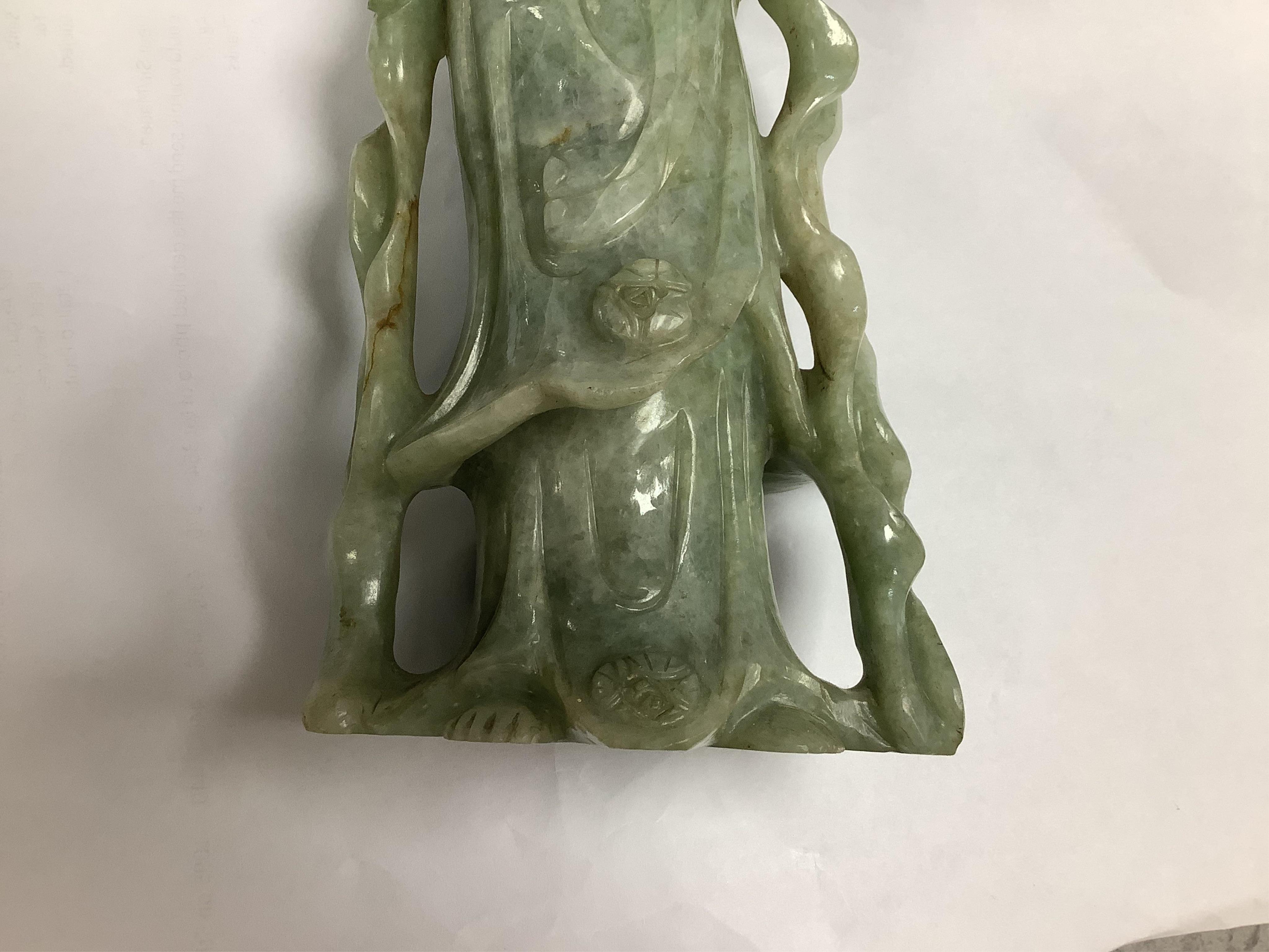 A Chinese jadeite carving of Guanyin, on associated hardwood stand, 38cm high. Condition - fair